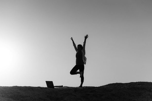 Silhouette of a person in a yoga pose against a vibrant sunrise.
